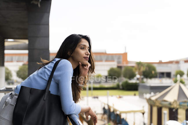 Vue latérale de la femme avec sac à main appuyé sur la rampe en ville — Photo de stock