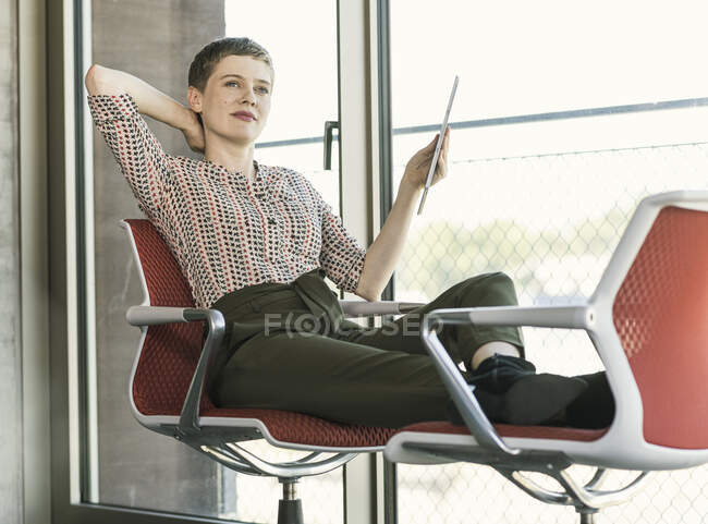Relaxado empresária segurando tablet no escritório — Fotografia de Stock