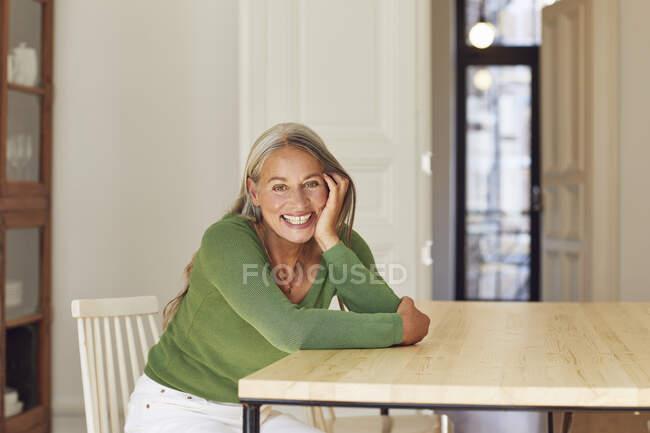 Alegre mujer día soñando por mesa en casa - foto de stock