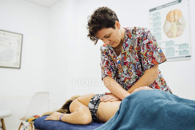 Feminino osteopata terapeuta dando de volta massagem para desportista no spa de saúde — Fotografia de Stock