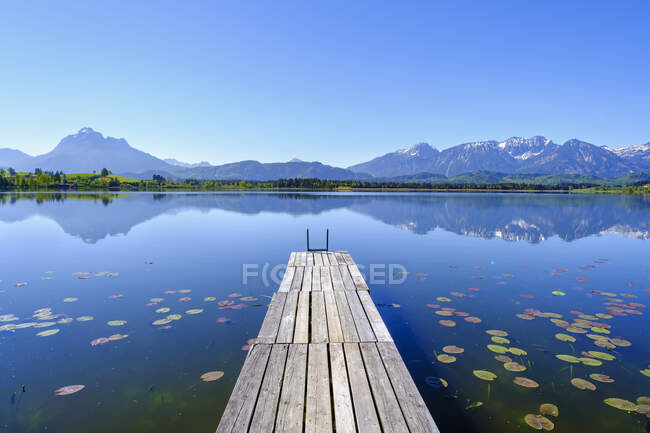 Jetée sur la rive du lac Hopfensee avec les montagnes de Tannheim en arrière-plan — Photo de stock