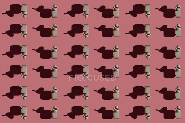 Patrón de pequeñas figuritas de burro marrón sobre fondo rojo pastel - foto de stock