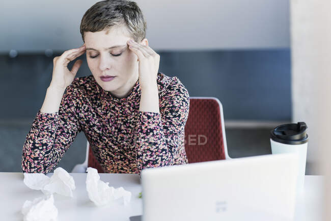 Businesswoman at desk in office having headaches - foto de stock