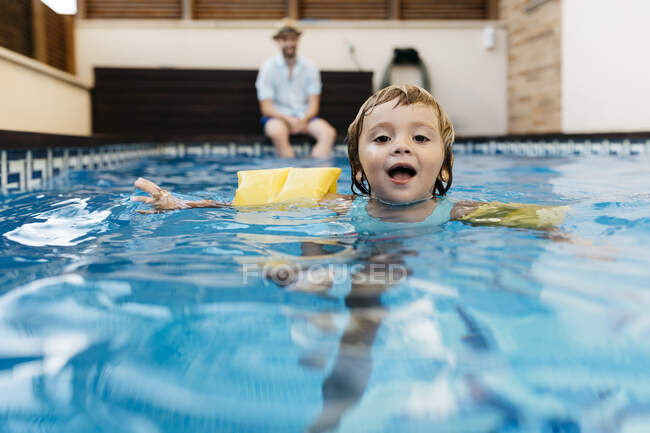 Little girl in swimming pool, her uncle on poolside — Stock Photo