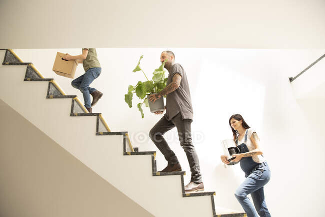 Famiglia che trasporta vari oggetti mentre sale sui gradini in un nuovo appartamento — Foto stock