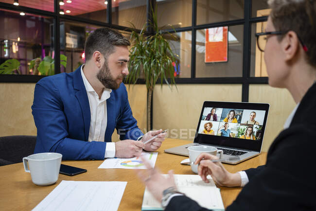Male and female professionals on video call during meeting in board room at office — Fotografia de Stock