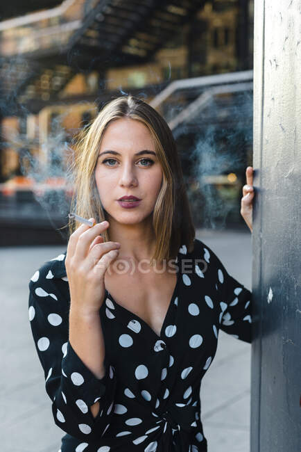Hermosa mujer fumando cigarrillos mientras está de pie en la ciudad — Stock Photo