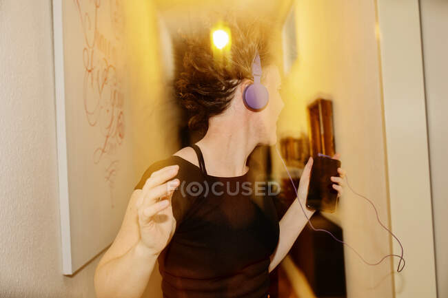 Unbekümmerte erwachsene Frau mit Kopfhörern tanzt zu Hause — Stockfoto