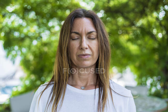 Mujer madura con los ojos cerrados de pie al aire libre - foto de stock