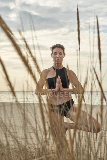 Woman practicing yoga while standing at beach — Foto stock