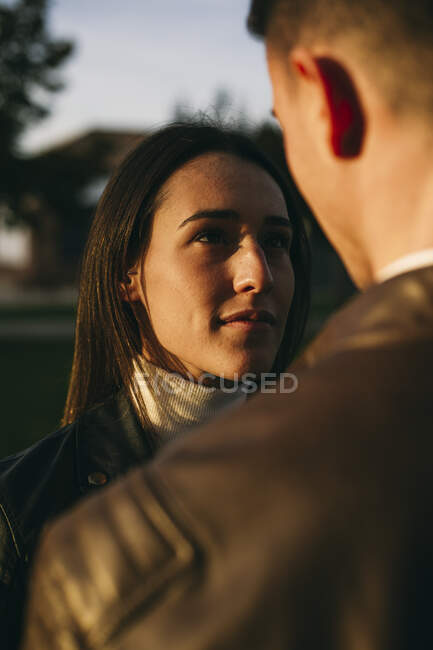 Дівчина дивиться на чоловіка, стоячи надворі під час заходу сонця. — стокове фото