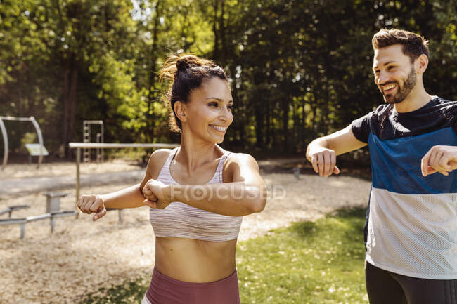 Hombre y mujer estirándose cerca de un sendero de fitness - foto de stock