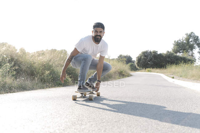 Bel homme skateboard sur la route contre ciel clair — Photo de stock