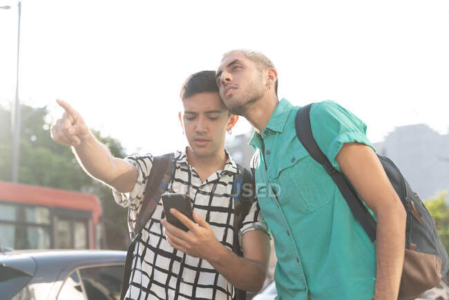 Junger Mann zeigt Freund mit Smartphone Richtung Stadt — Stockfoto