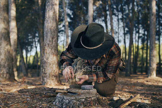 Bushcrafter preparando fuego para cocinar alimentos en el bosque - foto de stock