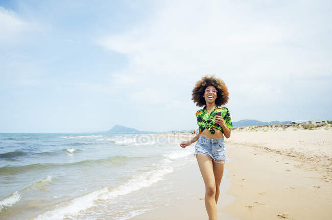 Молодая женщина бежит по пляжу — стоковое фото