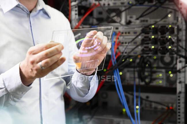 Primer plano del ingeniero que utiliza la tecnología inalámbrica mientras está de pie en la sala de servidores - foto de stock