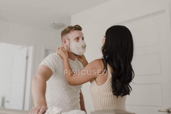 Frau bedeckt während COVID-19 das Gesicht ihres Partners mit Schutzmaske — Stockfoto