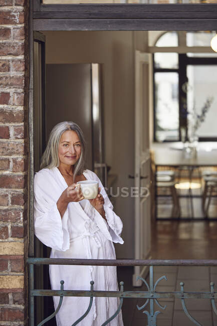 Улыбающаяся женщина пьет чай на балконе — стоковое фото