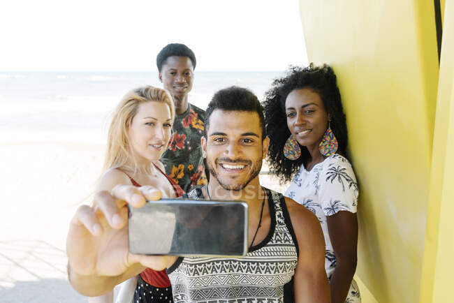 Amici prendere selfie mentre in piedi in rifugio bagnino in spiaggia — Foto stock