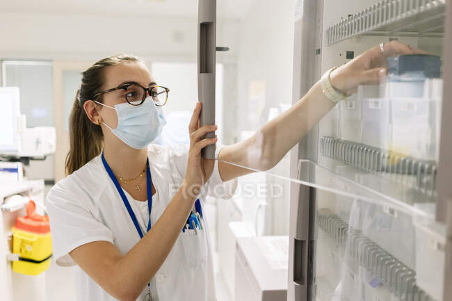 Médica que toma medicamentos do armário em farmácia no hospital — Fotografia de Stock