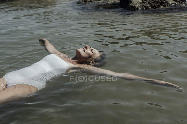 Femme âgée avec les yeux fermés relaxant sur la mer pendant la journée ensoleillée — Photo de stock
