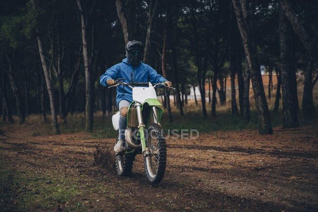Maschio adolescente cavalcare moto su strada sterrata nella foresta — Foto stock