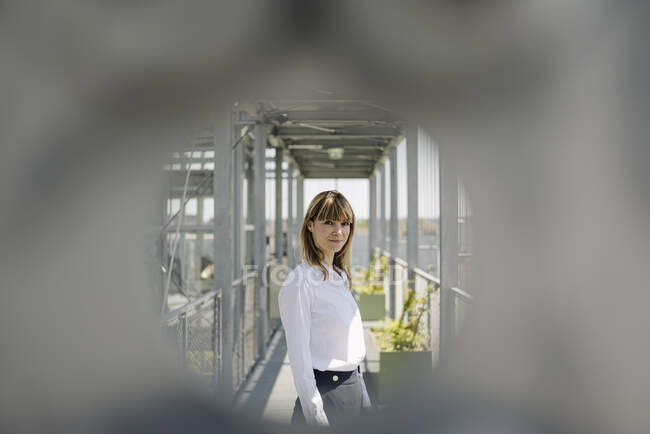 Selbstbewusste Geschäftsfrau steht im Gewächshaus, durch Metall gesehen — Stockfoto