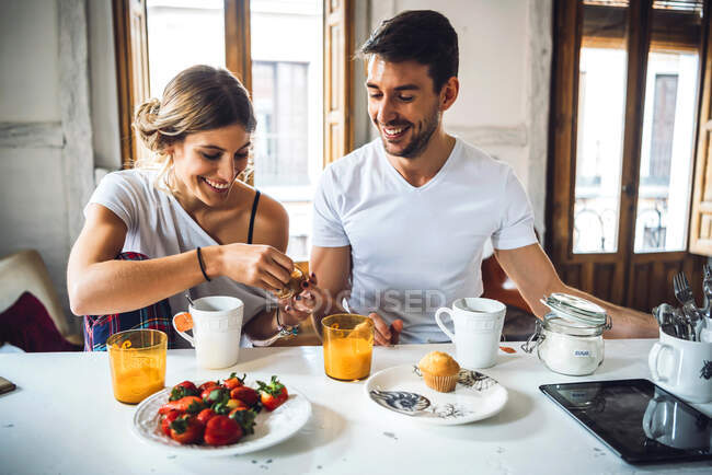 Щаслива молода пара сидить за столом і снідає вдома. — стокове фото