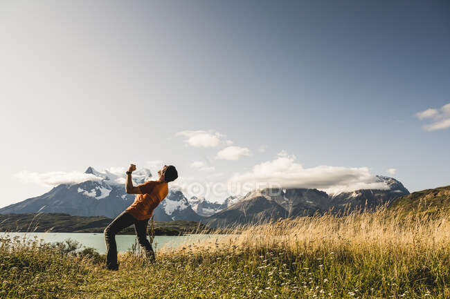 Homme montrant un geste gagnant alors qu'il se tenait près du lac Pehoe dans le parc national Torres Del Paine, Chili Patagonie, Amérique du Sud — Photo de stock