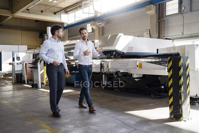 Business people discussing while walking by machine at factory — Stock Photo