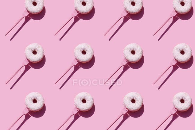 Patrón de horquillas con rosquillas dulces sobre fondo rosa - foto de stock