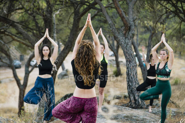 Women in tree pose exercising while standing on one leg in forest — Stock Photo