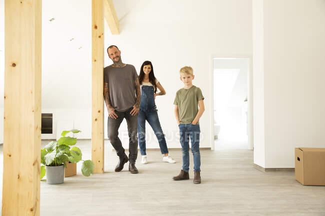 Семья стоит на лиственном полу на чердаке нового дома — стоковое фото