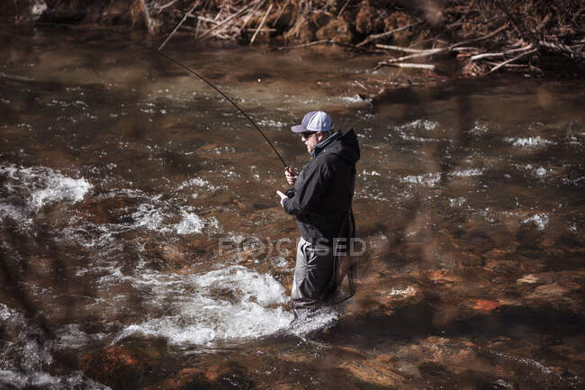 Mosca pescador casting en rápido fluir río en bosque - foto de stock