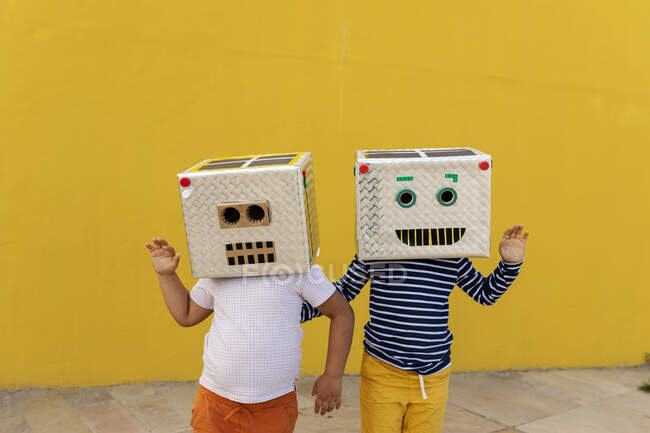 Друзья в костюмах роботов, размахивающие перед жёлтой стеной — стоковое фото