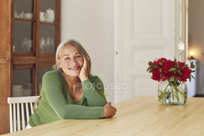 Mujer sonriente día soñando por la mesa en casa - foto de stock