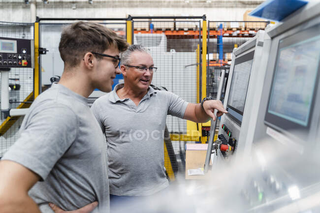 Male engineers brainstorming while testing machine at factory — Stock Photo