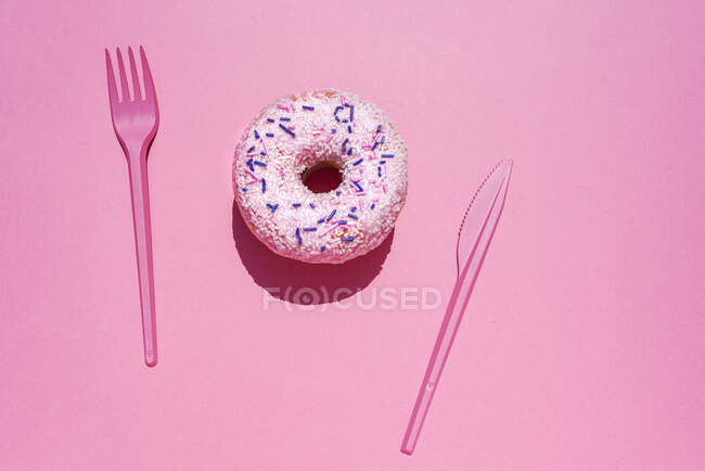 Studio shot of sweet doughnut and plastic cutlery — Stock Photo