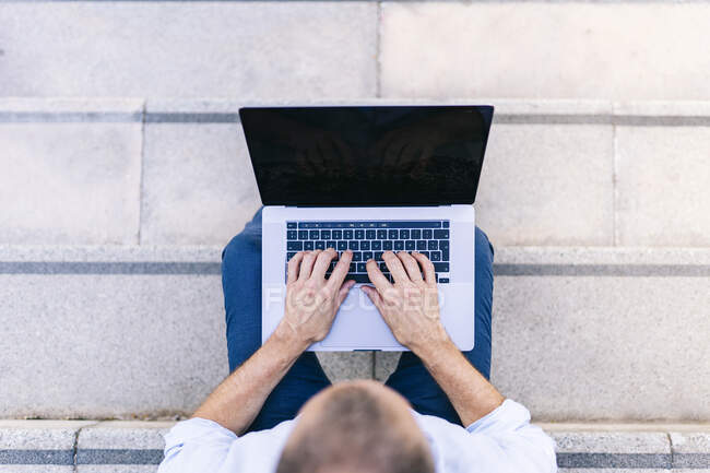 Geschäftsmann benutzt Laptop, während er auf Stufen sitzt — Stockfoto