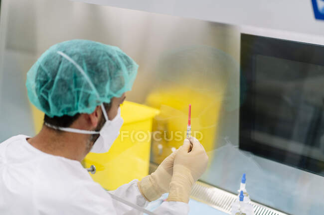 Primo piano del farmacista maschio che tiene la siringa in laboratorio visto attraverso il vetro — Foto stock