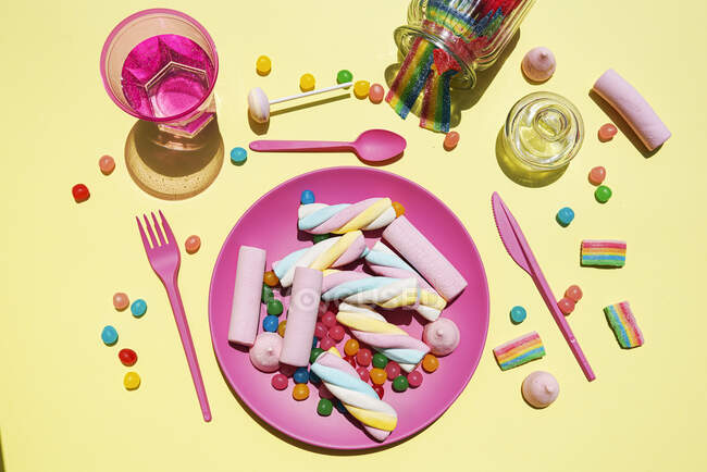 Studio shot of glass of water and plastic plate filled with various sweets — Stock Photo