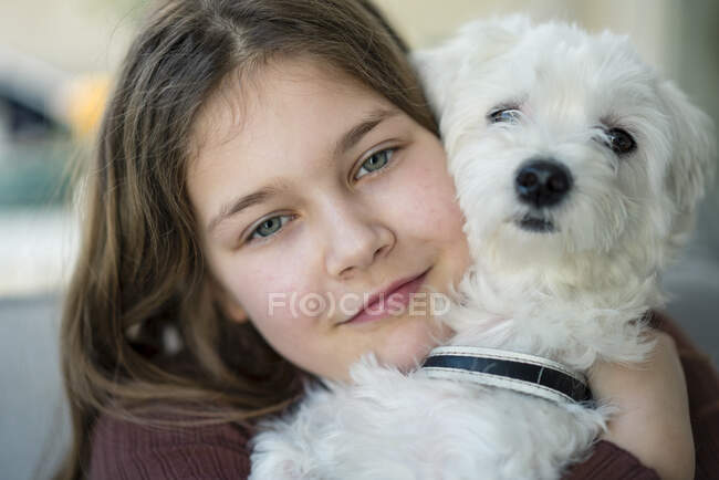 Nettes lächelndes Mädchen umarmt Hund im Wohnzimmer — Stockfoto