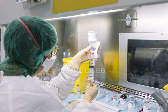 Primer plano de la científica femenina inyectando líquido en botella en el laboratorio - foto de stock