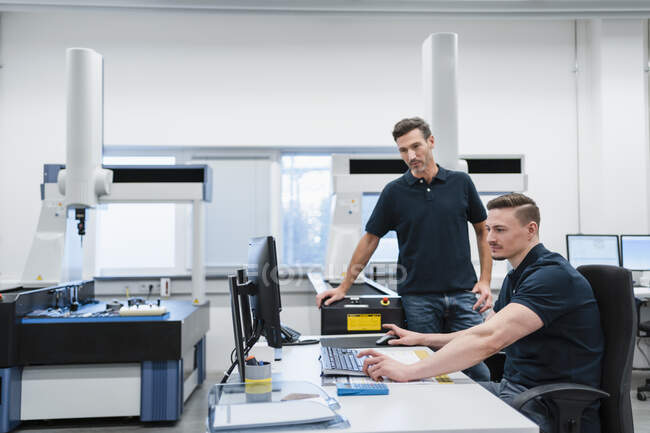 Male technician with colleague using computer in industry office — Stock Photo