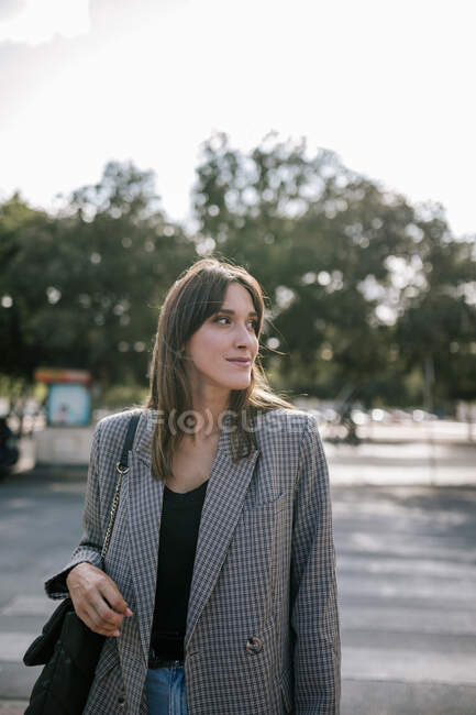 Молодая женщина смотрит в сторону, стоя на улице — стоковое фото
