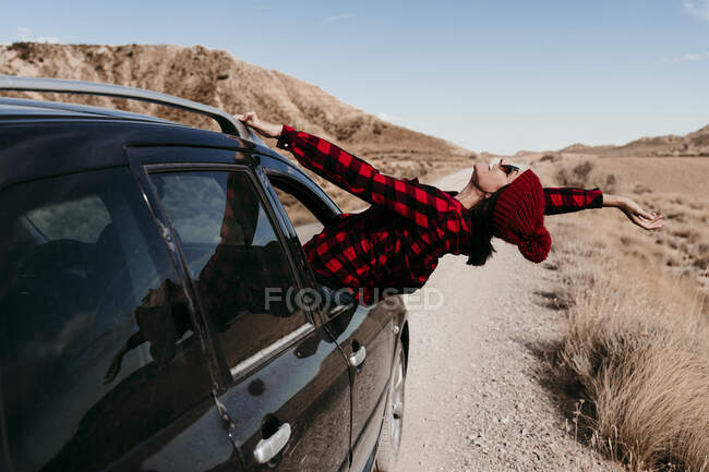 Іспанія, Наварра, Жіночий турист, що виходить з вікна автомобіля через брудну дорогу в Барденас Реалес. — стокове фото