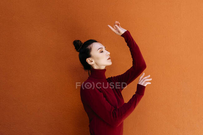 Woman with eyes closed dancing against orange wall — Stock Photo