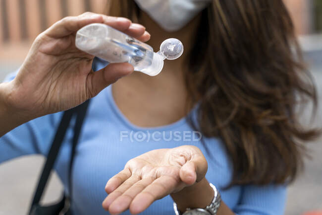 Mujer de negocios vertiendo desinfectante en la mano durante la pandemia - foto de stock