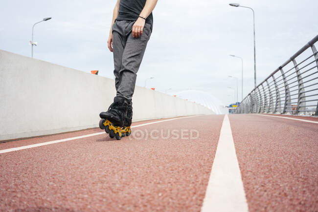 Legs of young man inline skating on bridge against sky in city — Foto stock